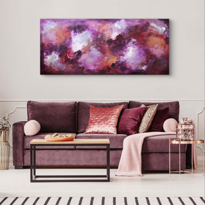 Large abstract artwork with vibrant purple, pink, and red hues displayed above a plush purple sofa with matching decorative pillows in a modern living room setting.