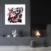 Monochrome abstract canvas art with bold red and black brushstrokes, displayed on dark wall with shelving and decorative objects.