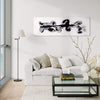 Monochrome abstract art painting on canvas displayed above a modern living room sofa with neutral-colored cushions. The painting features bold, expressive brushstrokes in black and white, creating a striking and minimalist visual statement. Surrounding the artwork are carefully arranged home decor elements, including a table lamp, stacked books, and a vase with natural floral branches, complementing the contemporary and refined aesthetic of the space.