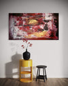 Large abstract landscape painting titled "The Edge Of a Dream" displayed on a white wall, featuring vibrant shades of red, orange, and brown. A black vase with red flowers is placed on a yellow side table in the foreground, adding a complementary accent to the painting.