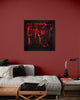 Vibrant abstract art on red wall | Square black framed painting with bold, expressive red and black brushstrokes in a modern living space with couch and decor
