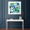 Vibrant abstract artwork with swirling brushstrokes in shades of green, blue, and purple, displayed on a white wall above a minimalist white console table in a modern, stylish interior setting.