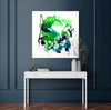 Gestural abstract painting with bold green and blue brushstrokes on a white canvas, displayed on a white console table against a dark grey wall.