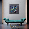 Vibrant abstract artwork | Colorful square canvas painting displayed on a grey wall above a modern green sofa with a metallic base | Captivating artistic expression with bold brushstrokes and dynamic hues