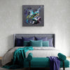 Taupe Green Art | Marvellous Dream 40x40" - Vibrant abstract painting featuring earthy green and purple hues on a grey canvas, displayed above a grey upholstered bed with green and purple accent pillows.