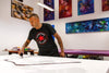 Large abstract paintings and modern art on display in a studio, with an artist working on a painting on an easel.