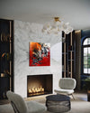 Large abstract artwork on red and white canvas in modern living room with marble wall, fireplace, and chandelier