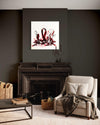 Large abstract painting displayed on dark wall above fireplace in cozy living room setting with beige armchair and wooden coffee table.