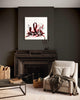 Large abstract painting displayed on dark wall above fireplace in cozy living room setting with beige armchair and wooden coffee table.