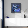 Abstract square canvas painting in blue and white hues featuring dynamic brushstrokes and textures, presented in a modern home decor setting with white cabinetry and dark accents.