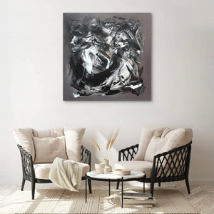 Large modern abstract painting titled "Taupe Abstraction | The Light Will Come" in a 100x100cm square canvas, displayed on the wall above a cozy living room setting with beige upholstered chairs and a small coffee table.