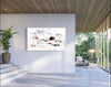Large abstract landscape art with earthy colors displayed on a white wall in a modern home interior with wooden ceiling and glass doors overlooking outdoor greenery.
