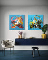 Vibrant abstract diptych paintings | Two large square abstract artwork featuring energetic, colorful brushstrokes and dynamic compositions on blue backgrounds, displayed on white brick wall in modern living room setting with dark furniture and decor.