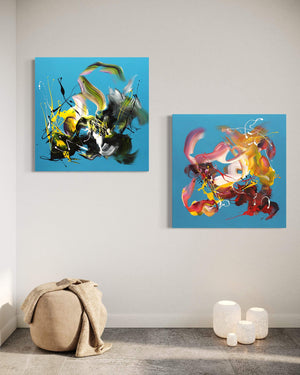 Two vibrant abstract paintings titled "Summer in the City I and II" displayed on a white wall. The paintings feature bold, colorful brush strokes and shapes in a variety of earthy tones, creating a dynamic and modern art piece. The paintings are placed in a minimalist setting, with a beige couch and decorative elements in the background, highlighting the artwork as the focal point of the room.