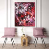 Vibrant abstract painting in shades of pink, red, and purple adorns the wall above two pink chairs and a wooden side table in a modern room setting.