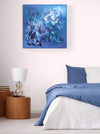 Blue abstract canvas painting displayed on a white wall in a bedroom setting with a blue bedding and a wooden nightstand.