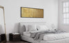 Large gold-toned abstract canvas art hanging above a modern white bed in a minimalist bedroom setting