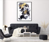Large abstract artwork with expressive black and yellow brushstrokes framed on the wall above a black modern sofa and coffee table in a minimalist living room setting.
