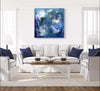 Large abstract artwork depicting a mermaid dance in shades of blue and white, displayed on the wall of a modern living room with white furniture and wooden accents.