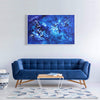 Large abstract landscape painting in shades of blue, displayed on a white wall above a navy blue sofa in a modern living room setting.