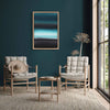 Geometric Painting | Teal Waters 24x36"
This abstract landscape painting with its bold teal and black geometric shapes is displayed in a modern living room setting. The painting is framed and hangs on a deep green wall, complementing the beige armchairs and side table in the room.