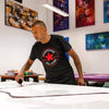 Contemporary abstract artwork in a variety of vibrant colors, including a large canvas on an easel with a man working on it, as well as several framed abstract paintings on the walls.
