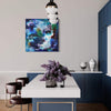 Large abstract painting of blue and green hues displayed on the wall above a modern dining table setting with a floral arrangement and decorative vases.