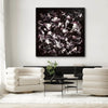 Dramatic abstract artwork in monochrome tones, framed and displayed on a white wall in a modern living room setting with plush white sofas and a glass-top coffee table.