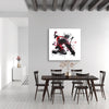 Large abstract black and white painting depicting dynamic, fluid brushstrokes on a white canvas, hanging above a rustic wooden dining table and chairs in a minimalist, modern interior setting.