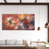 Large abstract painting of colorful autumn foliage displayed on the wall of a modern, minimalist living room with wooden accents and pendant lighting.