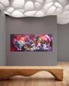 Large abstract artwork with vibrant colors displayed on a gray wall against a backdrop of white organic shapes, mounted on a wooden bench in the modern gallery setting.