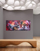 Large abstract artwork with vibrant colors displayed on a gray wall against a backdrop of white organic shapes, mounted on a wooden bench in the modern gallery setting.