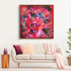 Vibrant abstract artwork with dancing hues of red, pink, and blue in a square frame, adding a bold statement to the modern living room setting.