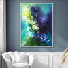 Vibrant abstract floral artwork displayed in a modern living room setting. The large canvas features a dynamic blend of blue, green, and purple hues, creating a captivating and contemporary piece of art. The artwork is framed and prominently displayed on the wall, complementing the neutral-toned furnishings and decor in the room.