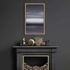 Minimalist abstract landscape art in a modern black frame, displayed on the wall above a dark fireplace mantel adorned with decorative objects.
