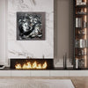 Dramatic black and white abstract painting on marble wall above modern fireplace with crackling flames, flanked by elegant bookshelves in stylish living room interior