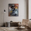 Large abstract canvas painting with vibrant colors and dynamic brushstrokes, displayed on a white wall in a modern living room setting with a wooden chair and floor lamp.