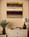 Mixed media abstract painting depicting colorful textured layers and patterns, surrounded by a wooden frame and displayed in a cozy home interior setting with a decorative vase and books.