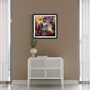 "Vibrant Abstract Artwork" - Framed print depicting a colorful, abstract landscape displayed on a wall above a white cabinet in a modern interior setting.
