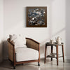 Swept In A Moment II 20x20" - Abstract square painting showcasing a dynamic mix of gray, black, and white brushstrokes against a neutral background, displayed on the wall of a modern living room setting with a comfortable armchair and side table.