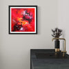 "Vibrant Abstract Art" - Colorful framed painting with bold, expressive brushstrokes in shades of red, orange, and black hanging on a wall above a dark wooden console table with a decorative vase.