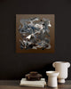 Swept In A Moment II 20x20" - Abstract square artwork featuring dynamic brushstrokes and muted tones displayed on a dark wall, complemented by decorative objects on a wooden shelf.