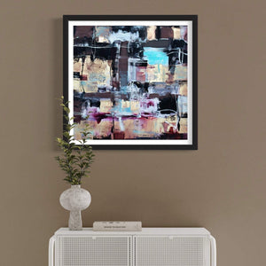 Framed abstract art print with vibrant earthy-toned colors and geometric shapes, displayed on a neutral-colored wall above a white cabinet.