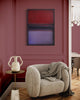 Framed abstract Rothko-style painting with bold red and purple tones, displayed on pink wall above a cozy beige armchair in a modern interior.