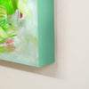 Large vibrant abstract canvas art with earthy green, pink, and white tones displayed on a white wall