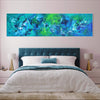 Teal Abstract | Aqua Dreamscape 24x90" - Large abstract landscape painting in vibrant blue and green tones, displayed above a cozy bedroom setting with a tufted headboard and white bedding.