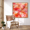 Large abstract painting of vibrant red, orange, and pink tones displayed in a modern, minimalist living room setting with a wooden armchair and bamboo blinds.
