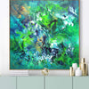 Colorful abstract painting depicting a vibrant, energetic scene with a mix of green, blue, and yellow brushstrokes. The canvas is framed and appears to be displayed on a table or shelf, surrounded by decorative vases and other objects.