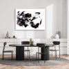 Large abstract black and white artwork depicting dynamic motion on display in modern dining room setting with wooden table and chairs.