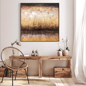 Textured abstract painting featuring gold and earthy tones, showcased in a modern home setting with wooden furniture and decor.